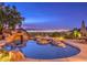 Luxury pool and spa with waterfall feature at twilight, overlooking city lights at 3 Palmbrook Ln, Henderson, NV 89052