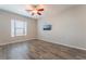 Comfortable bedroom with wood-look flooring, large window, ceiling fan and mounted TV at 421 Point Sur Ave, Las Vegas, NV 89138