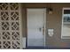 Tan home's secured white front door with mailbox, and decorative concrete wall, on a sunny day at 4709 W Alpine Pl, Las Vegas, NV 89107