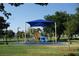 Community playground with a blue shade structure covering play equipment surrounded by a grassy area at 4709 W Alpine Pl, Las Vegas, NV 89107
