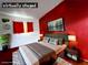 This virtually staged bedroom has a red accent wall and plush bedding at 5330 E Charleston Blvd # 5, Las Vegas, NV 89142