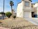 Exterior view of a townhouse with a one car garage, desert landscaping, and blue recycling cans at 5330 E Charleston Blvd # 5, Las Vegas, NV 89142