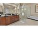 Well-lit bathroom with walk-in shower, bathtub, and wood cabinets for ample storage at 135 E Harmon Ave # 407, Las Vegas, NV 89109