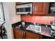 Close up of kitchenette with microwave, kettle, sink, black countertop and wood cabinets perfect for simple meal preparation at 135 E Harmon Ave # 407, Las Vegas, NV 89109