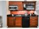 Compact kitchenette boasts microwave, sink, and mini-fridge integrated into custom wooden cabinetry with sleek black countertop at 135 E Harmon Ave # 407, Las Vegas, NV 89109