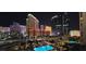 Night view of a pool surrounded by palm trees, in front of glowing Las Vegas hotels at 135 E Harmon Ave # 407, Las Vegas, NV 89109