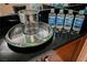 Close-up of a wet bar with a stainless steel ice bucket and bottled water on a black countertop at 135 E Harmon Ave # 407, Las Vegas, NV 89109