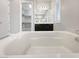 Primary bath showcasing soaking tub, dark vanity, white shutters, and access to walk-in closet at 3408 Isle Dr, Las Vegas, NV 89141