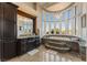 Well-lit bathroom featuring a soaking tub, elegant cabinetry and windows with great views of the landscape at 2870 Quartz Canyon Dr, Henderson, NV 89052