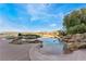 Backyard pool with rock waterfall feature and view of houses and a golf course at 2870 Quartz Canyon Dr, Henderson, NV 89052