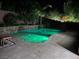 Beautiful in-ground pool featuring vibrant green lighting, a stone waterfall, and a tranquil setting at 5873 Skyfall Ct, Las Vegas, NV 89135