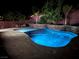 Inviting in-ground pool illuminated with vibrant blue lighting and complemented by a stone waterfall feature and lush landscaping at 5873 Skyfall Ct, Las Vegas, NV 89135