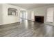 Open living room with a brick fireplace, grey laminate flooring, and natural lighting at 6137 W Oakey Blvd # A, Las Vegas, NV 89146