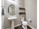 Stylish powder room featuring a pedestal sink, toilet, and decorative floating shelves at 8351 Agave Bloom St, Las Vegas, NV 89131