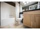 Bathroom featuring a tub with white tiles, complemented by a vanity with natural wood cabinets and dark countertops at 230 E Flamingo Rd # 212, Las Vegas, NV 89169