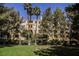 Multi-story building surrounded by trees, green grass and a blue sky overhead at 230 E Flamingo Rd # 212, Las Vegas, NV 89169