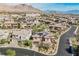 An aerial view shows the house surrounded by other homes in a neighborhood with mountain views at 12002 Tramonto Ave, Las Vegas, NV 89138