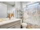 Bright bathroom with a gray vanity, updated faucet, and tiled shower with marble curtain at 2391 Dalewood Ave, North Las Vegas, NV 89086