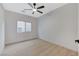 Cozy bedroom with a window, neutral walls, a ceiling fan, and light wood-look floors at 11119 Cantoria Ct, Las Vegas, NV 89141