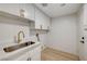 Well-lit laundry room with white cabinets, gold hardware, and stainless steel sink at 11119 Cantoria Ct, Las Vegas, NV 89141