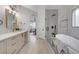 Bright and airy main bathroom with double vanity, a standalone tub, and a glass-enclosed shower at 11119 Cantoria Ct, Las Vegas, NV 89141