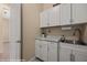 Well-organized laundry room with white cabinetry, sink, and marble countertops at 1143 Tortoise Mountain Dr, Mesquite, NV 89034