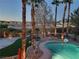 Well-maintained backyard with a pool, palm trees, and lighting at 9012 Alpine Peaks Ave, Las Vegas, NV 89147