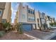 Modern three-story home with a blue garage door and landscaped yard at 8089 Misty Canyon Ave, Las Vegas, NV 89113