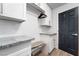 Bright laundry room featuring white cabinets, granite countertops, subway tile, and a built-in ironing board at 2144 Paganini Ave, Henderson, NV 89052