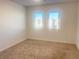 Simple bedroom with neutral colored walls and carpet, and two windows at 629 Soaring Wings Ave, Las Vegas, NV 89183