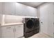 Laundry room featuring modern LG washer and dryer, white shaker cabinets, and designer backsplash at 37 Reflection Shores Ln, Henderson, NV 89011