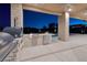 Outdoor kitchen with built-in grill, pizza oven, refrigerator, and a view of the pool at night at 37 Reflection Shores Ln, Henderson, NV 89011