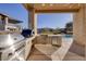 An outdoor kitchen has a stainless steel grill, pizza oven, refrigerator and faces the home's pool and fire pit at 37 Reflection Shores Ln, Henderson, NV 89011