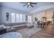 Open living room showcasing a sectional sofa, large windows, and an open floor plan to the kitchen at 5378 Pendini Point Ct, Las Vegas, NV 89141