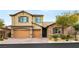 Two-story house with tan siding, brown garage doors, and stone accents at 7563 Saguaro Cactus Ave, Las Vegas, NV 89178