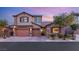 Two-story house with tan siding, brown garage doors, and stone accents at 7563 Saguaro Cactus Ave, Las Vegas, NV 89178