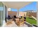 Covered patio boasts ample seating overlooking the backyard with well-maintained artificial turf at 8990 Rolling Pietra St, Las Vegas, NV 89166