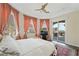 Inviting bedroom featuring a ceiling fan, large windows with peach curtains, an entertainment center, and an outside patio at 7192 Polita Ct, Las Vegas, NV 89156