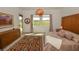 Well-lit bedroom with neutral tones, a wood headboard, patterned rug, and bright outdoor view at 12457 Heritage Bend Dr, Las Vegas, NV 89138