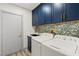 Laundry room with dark blue cabinets and mosaic backsplash at 1613 Shadow Rock Dr, Las Vegas, NV 89117