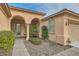 Inviting entryway with arched entry, mature shrubs, and a paved walkway at 5124 Pensier St, Las Vegas, NV 89135