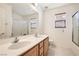 Bright bathroom featuring a double sink vanity, large mirror, and a shower/tub combo with sliding glass doors at 11276 Accademia Ct, Las Vegas, NV 89141