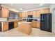 Kitchen with an island, wood cabinets, and black appliances at 11276 Accademia Ct, Las Vegas, NV 89141