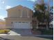 Two-story house with tan exterior, white garage door, and landscaping at 2525 Huber Heights Dr, Las Vegas, NV 89128