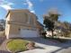 Two-story house with tan exterior, white garage door, and landscaping at 2525 Huber Heights Dr, Las Vegas, NV 89128