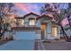 Two-story house with a landscaped front yard, driveway, and attached garage at dusk at 295 Blackstone River Ave, Las Vegas, NV 89148