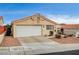 Tan stucco house featuring a white garage door and nicely landscaped front yard at 408 Matecumbe Way, Boulder City, NV 89005