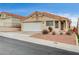 Single story home with a tan stucco exterior, a two-car garage, and desert landscaping at 408 Matecumbe Way, Boulder City, NV 89005