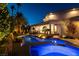 A luxurious backyard showcasing a sparkling blue pool and jacuzzi surrounded by lush landscaping and ambient lighting at 7880 Dana Point Ct, Las Vegas, NV 89117