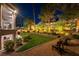 Beautifully landscaped backyard with manicured lawn, mature trees, crushed gravel, and two chairs to enjoy the view at 7880 Dana Point Ct, Las Vegas, NV 89117